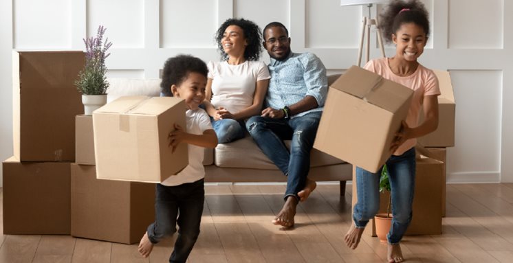 First time home owners watch their kids run with boxes as the move into their new home