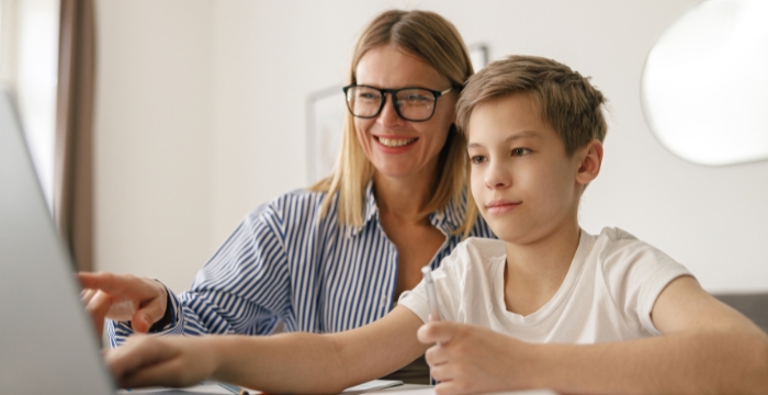 Adult and child smiling, on a laptop.
